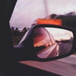 Malowniczy widok tętniącego życiem zachodu słońca odbijającego się w bocznym lusterku samochodu podczas jazdy przez Puerto Plata na Dominikanie.