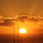 Zapierająca dech w piersiach sylwetka żaglówki na tle tętniącego życiem zachodu słońca na Dominikanie.