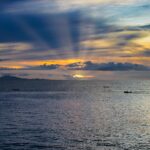 Dramatyczny zachód słońca nad oceanem Puerto Plata z łodziami i świecącym niebem.