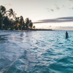 Najlepsze trasy wycieczek objazdowych po Dominikanie Sylwetka na spokojnej plaży w Punta Cana o zmierzchu, rejestrująca spokojną tropikalną scenę.