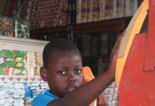 Dominikana na własną rękę – poradnik dla backpackerów Młody chłopak w niebieskim stroju korzystający ze staromodnego automatu telefonicznego w Santo Domingo na Dominikanie.