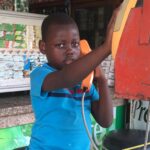 Młody chłopak w niebieskim stroju korzystający ze staromodnego automatu telefonicznego w Santo Domingo na Dominikanie.