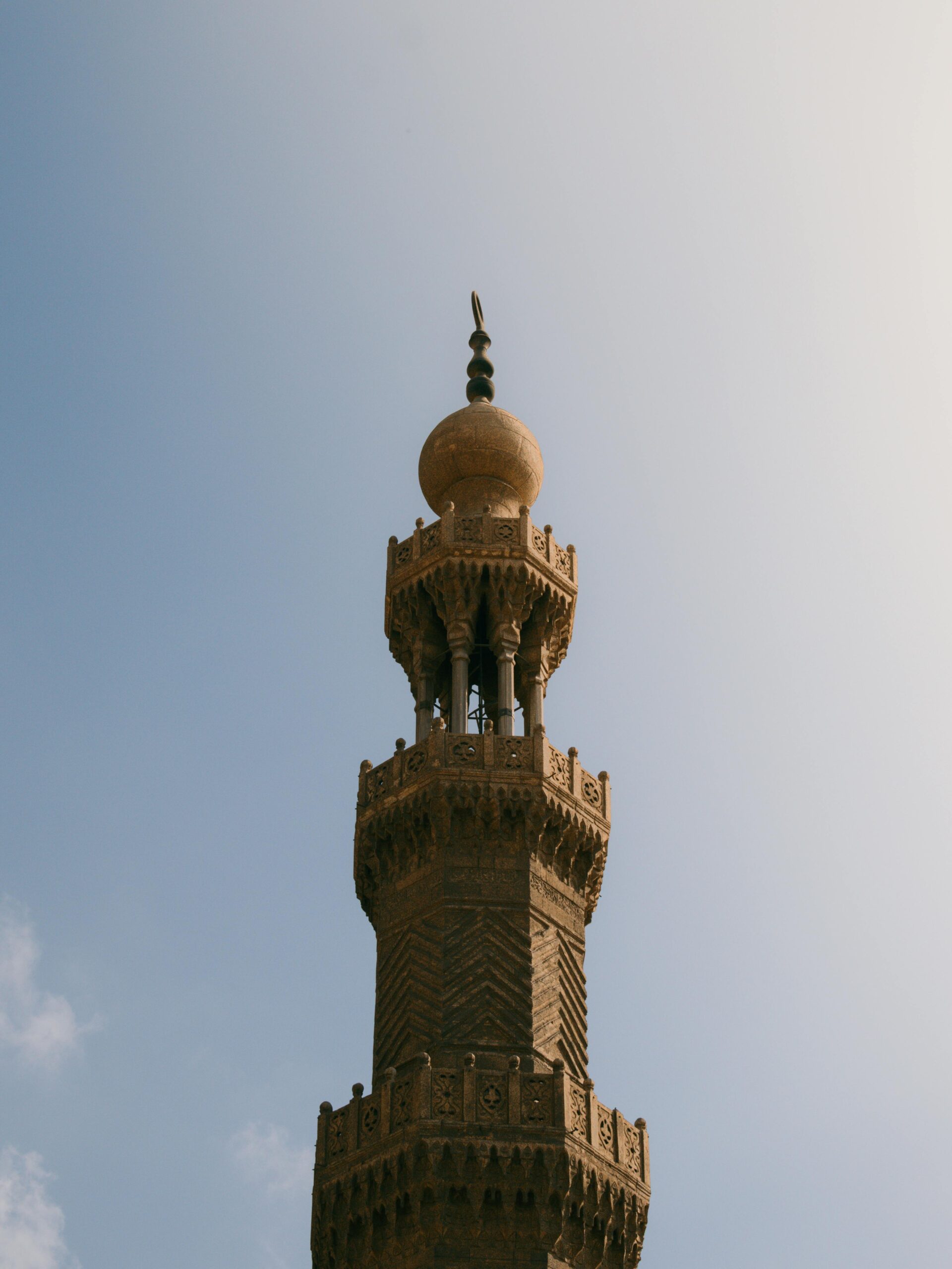 Wysoki, ozdobny minaret wznoszący się na tle czystego nieba, symbolizujący historyczną architekturę islamską.