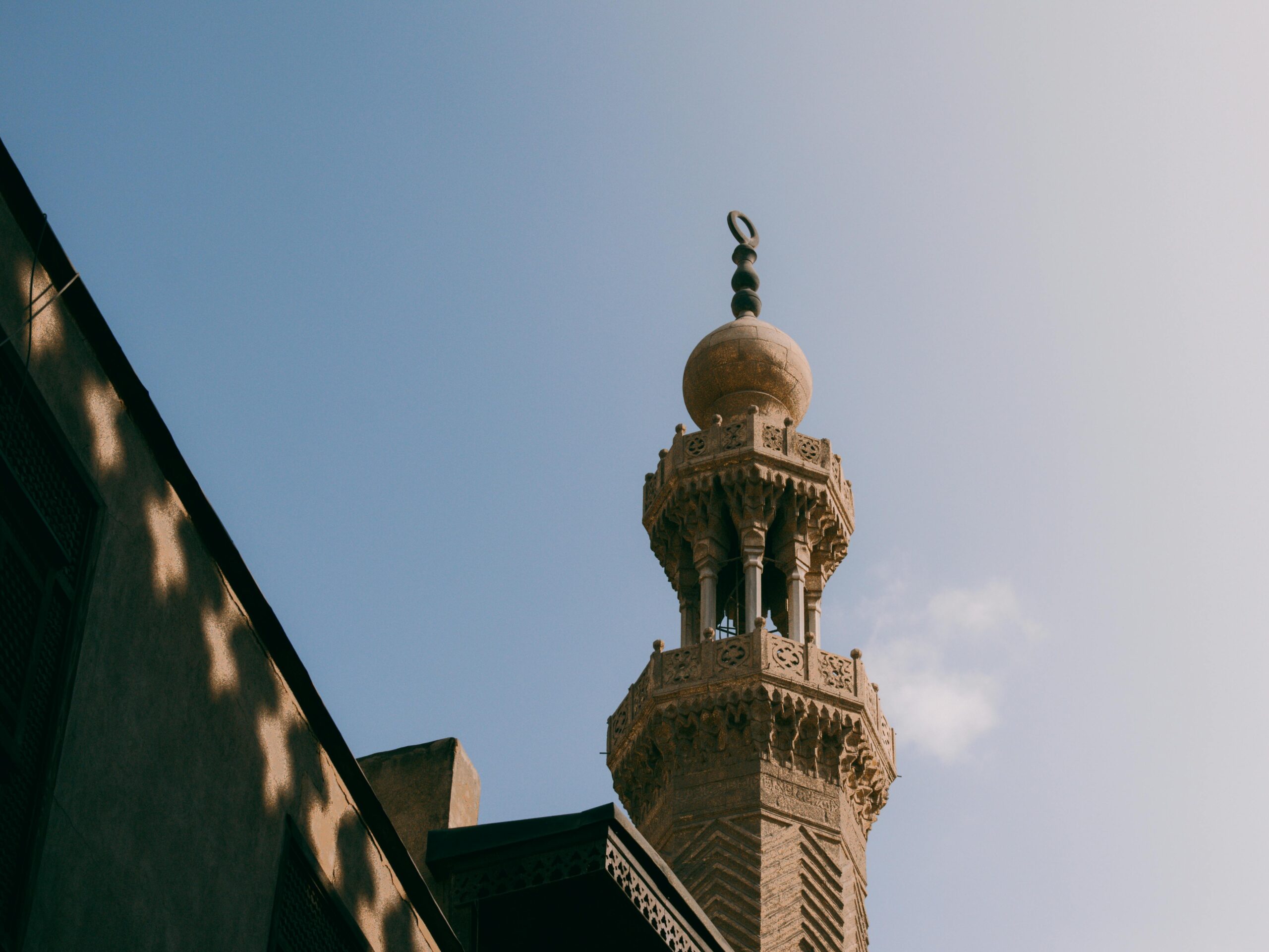 Elegancki minaret sięgający ku czystemu, błękitnemu niebu i ukazujący misterne detale architektury islamskiej.