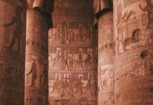 Turysta zwiedzający misternie rzeźbione kolumny świątyni Dendera w Egipcie.