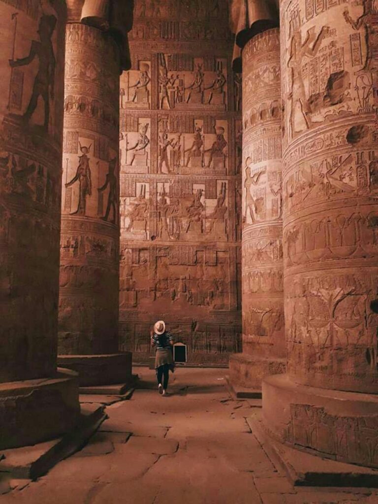 Turysta zwiedzający misternie rzeźbione kolumny świątyni Dendera w Egipcie.