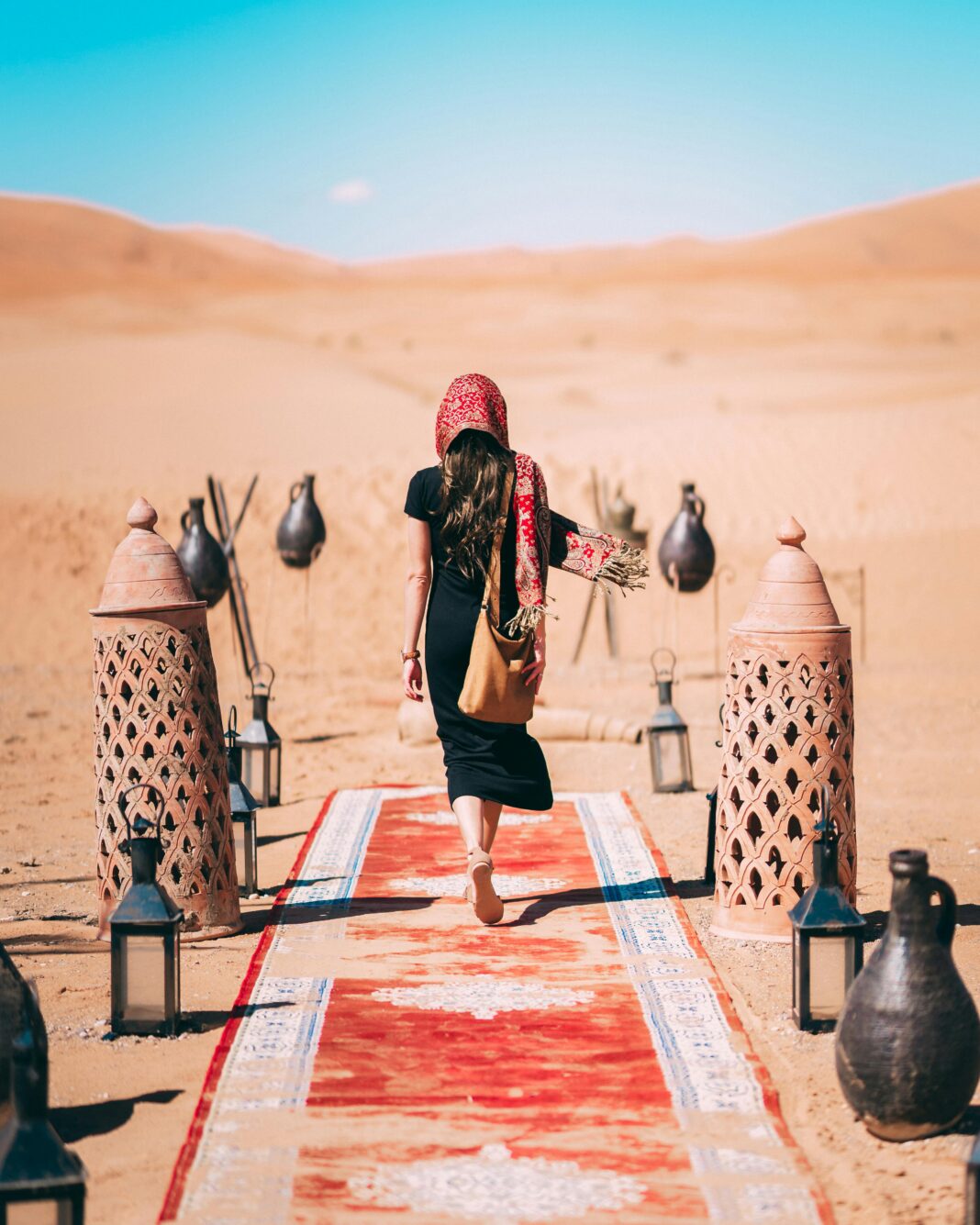 Kobieta w czarnej sukience spacerująca po pustyni Al Wahat Al Dakhla w Egipcie.