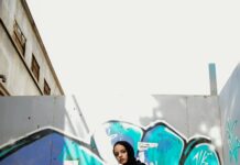 Stylowa kobieta stojąca pewnie przed tętniącą życiem ścianą graffiti w Kairze.