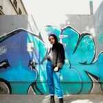 Stylowa kobieta stojąca pewnie przed tętniącą życiem ścianą graffiti w Kairze.