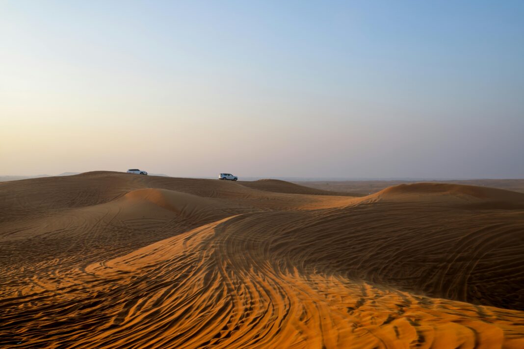 Przemierzanie samochodem przez spokojne pustynne wydmy, uchwycenie esencji pustynnego safari o świcie.
