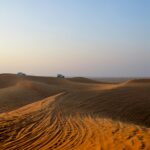 Przemierzanie samochodem przez spokojne pustynne wydmy, uchwycenie esencji pustynnego safari o świcie.