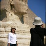 Turyści pozują i robią zdjęcia przy kultowym Wielkim Sfinksie w Gizie w Egipcie.