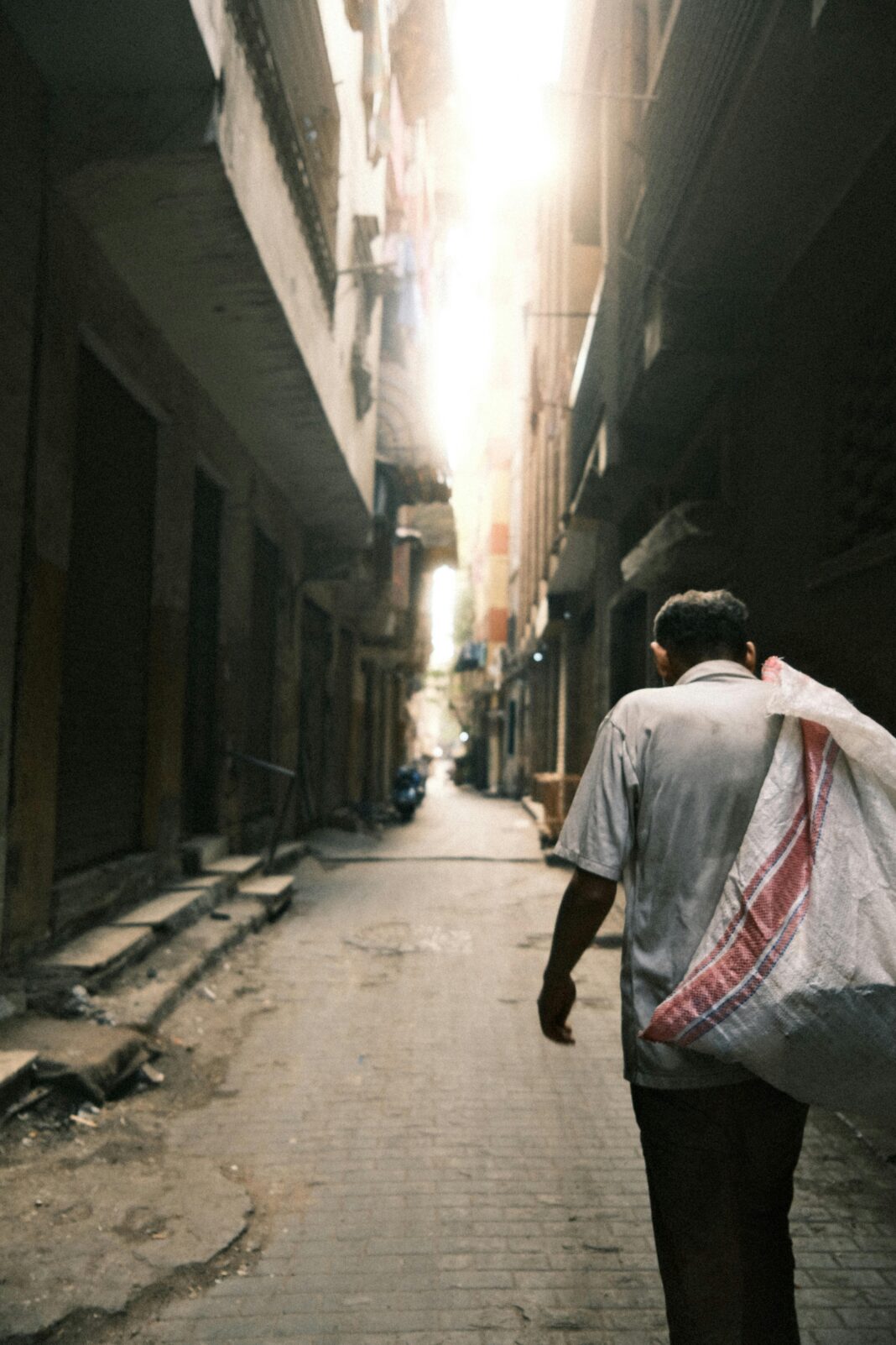 Mężczyzna spacerujący nasłonecznioną uliczką w historycznym Kairze w Egipcie.