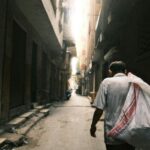 Egipt w czasach kolonializmu – wpływy europejskie Mężczyzna spacerujący nasłonecznioną uliczką w historycznym Kairze w Egipcie.