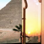 Zapierający dech w piersiach widok zachodu słońca na piramidę w Egipcie przez szklane drzwi balkonowe.