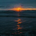 Spokojna scena zachodu słońca podkreślająca fale oceanu i żywe odbicie nieba.