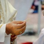 Zbliżenie na księdza udzielającego Komunii Świętej uczestnikowi w Guayaquil w Ekwadorze.