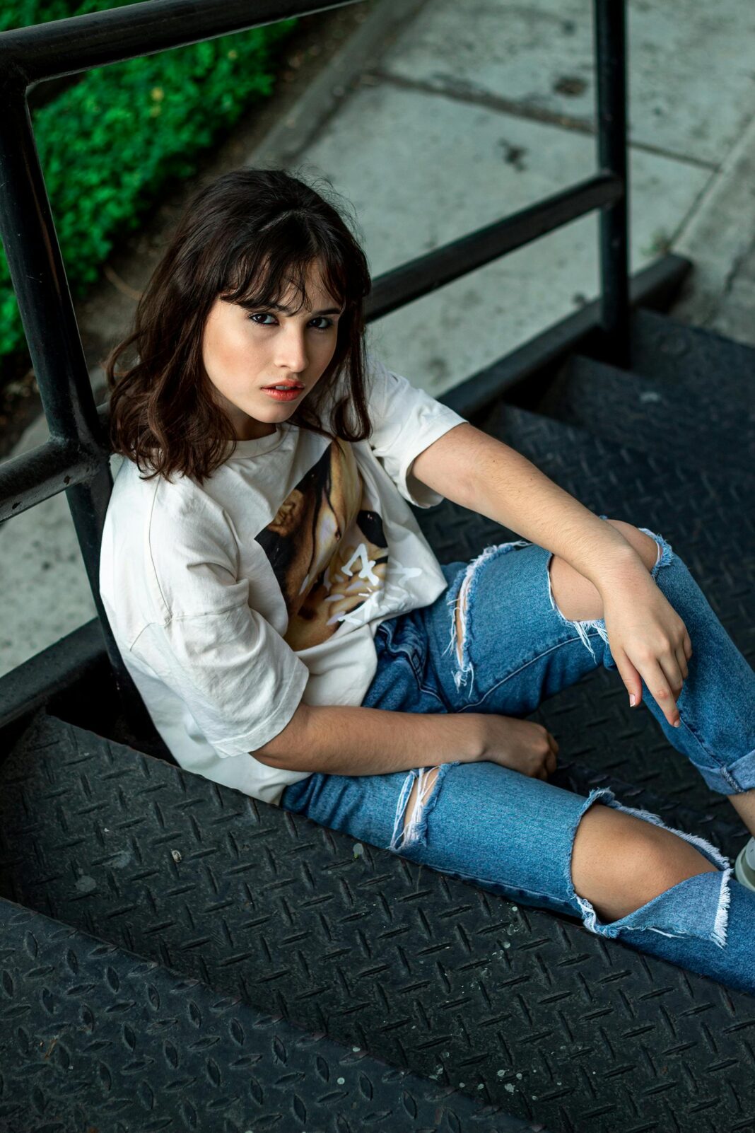 Stylowa kobieta z długimi włosami pozuje swobodnie na schodach w Samborondón w Ekwadorze.