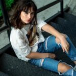 Stylowa kobieta z długimi włosami pozuje swobodnie na schodach w Samborondón w Ekwadorze.