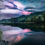 Spokojny widok na rzekę o zachodzie słońca w bujnym lesie deszczowym Ekwadoru, odzwierciedlający tętniące życiem niebo.