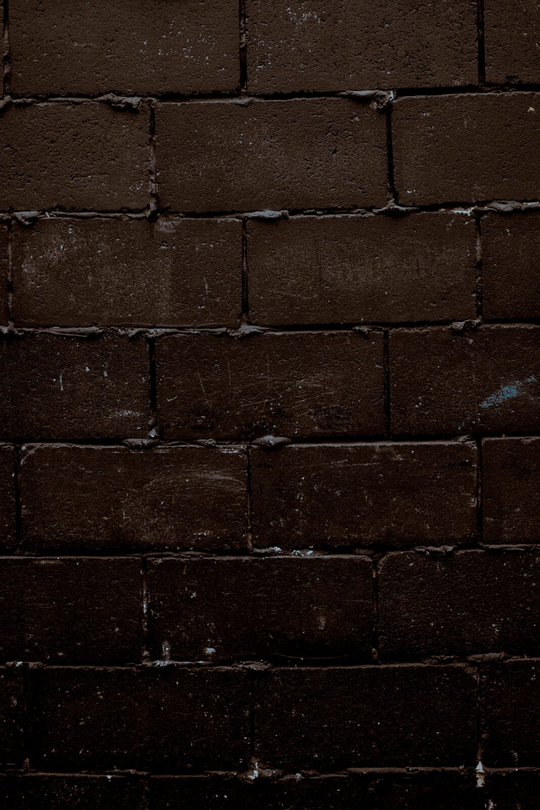 Zbliżenie tekstury ciemnego, szorstkiego muru, idealnego do tła.