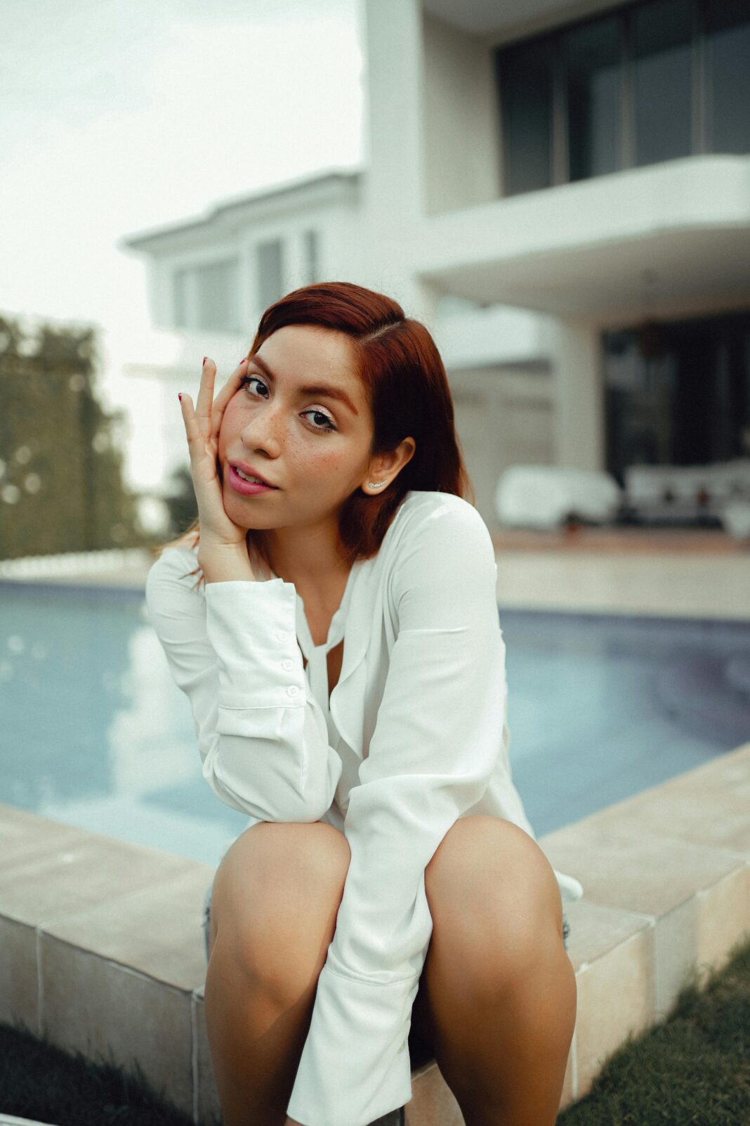 Elegancki portret młodej kobiety z rudymi włosami pozującej przy basenie w Ekwadorze.