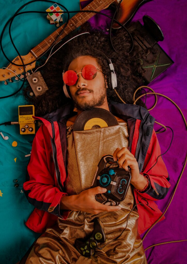 Mężczyzna z afro i słuchawkami słuchający muzyki retro w otoczeniu zabytkowych przedmiotów.