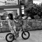Młoda dziewczyna jedzie na rowerze przed komisariatem policji w Sagadzie. 