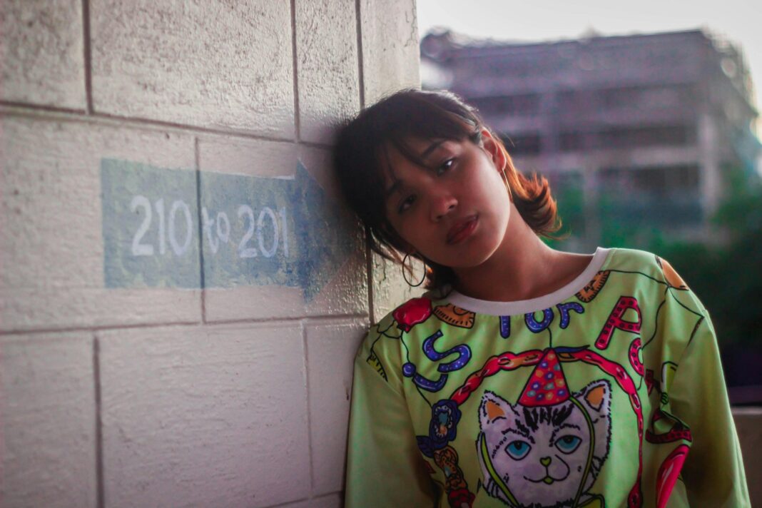 filipiny Portret młodej kobiety opartej o ścianę w miejskim tle, prezentującej kolorową modę na Filipinach.