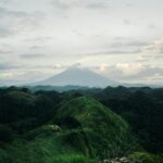 La Union: Raj dla surferów na północnym Luzonie Zapierający dech w piersiach widok z lotu ptaka na wulkan Mayon otoczony bujnymi wzgórzami pod zachmurzonym niebem.