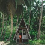 Scena na tropikalnej plaży w San Vicente na Filipinach z chatą, palmami i kobietą w bikini.