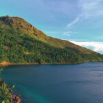 Piękne tropikalne wybrzeże z bujnymi górami i czystymi wodami oceanu pod jasnym niebem.