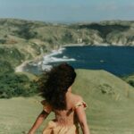 Kobieta stoi na trawiastym wzgórzu z widokiem na wspaniałe wybrzeże w dolinie Cagayan na Filipinach.