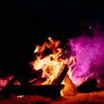 Tętniące życiem zimowe ognisko oświetlające śnieg i tworzące ciepły kontrast na tle ciemnego nocnego nieba.