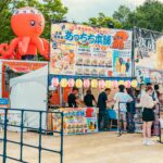 Kolorowe stoisko z japońskim jedzeniem podczas tętniącego życiem festiwalu na świeżym powietrzu z różnymi potrawami i oznakowaniem.