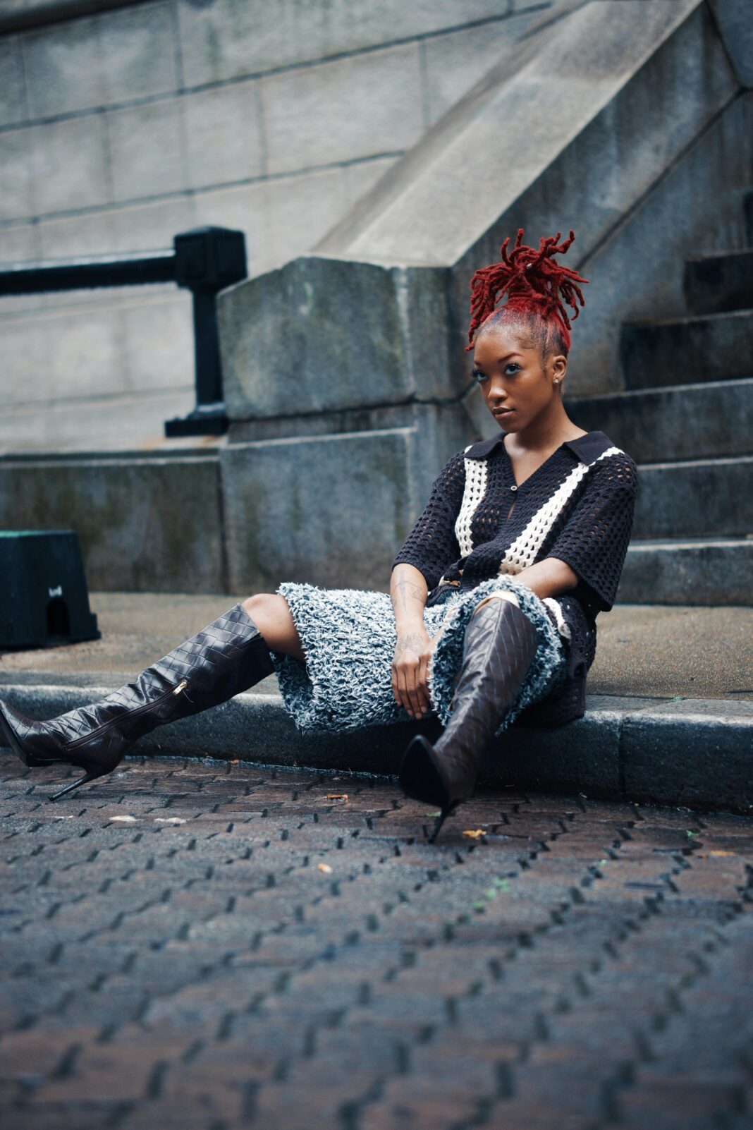 Młoda kobieta o rudych włosach siedząca na ulicy Georgetown prezentuje nowoczesną modę miejską.