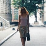 Pewna siebie kobieta w spódnicy w panterkę i żółtych szpilkach idzie ulicą Georgetown. 