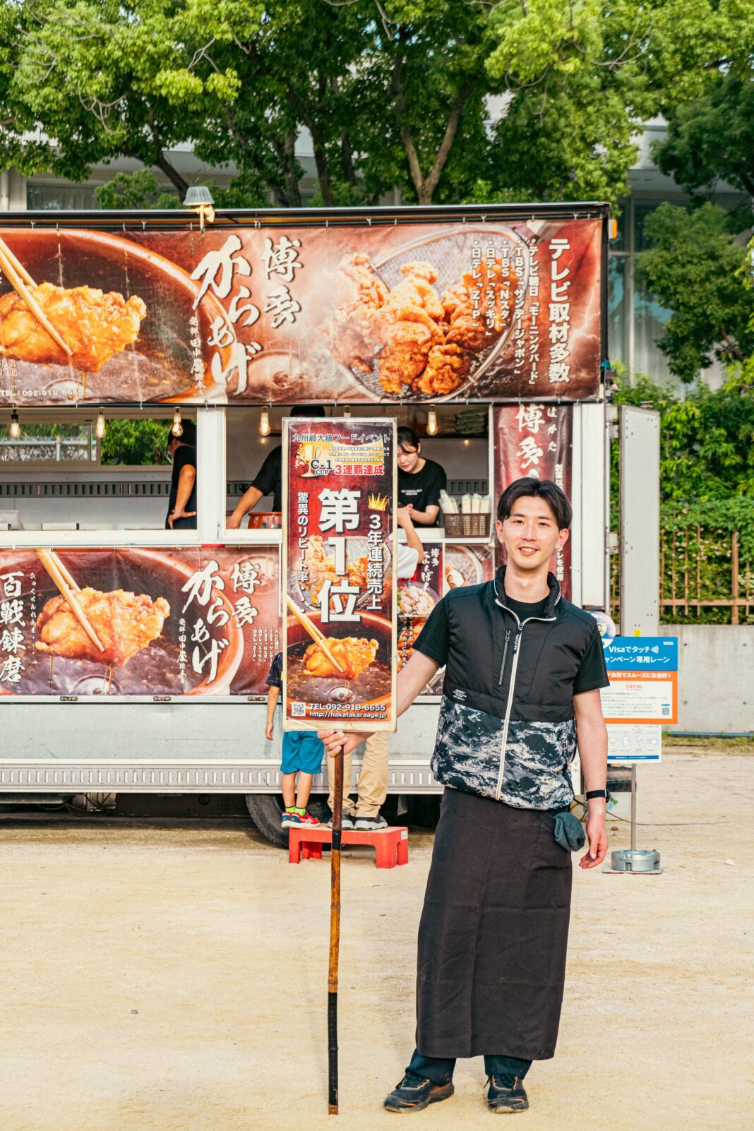 Wesoły sprzedawca oferuje smażone przysmaki podczas tętniącego życiem festiwalu japońskiej kuchni.