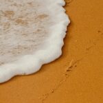 Zbliżenie na fale oceanu spotykające się ze złotym piaskiem na plaży w Gujanie.