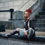 Modna kobieta z rudymi włosami siedząca na schodach miasta w Georgetown w Gujanie.