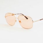 Stylowe okulary przeciwsłoneczne typu aviator z różowymi przyciemnianymi soczewkami na eleganckim białym tle.