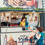 Uliczny sprzedawca żywności obsługuje klientów na tętniącym życiem rynku japońskim.