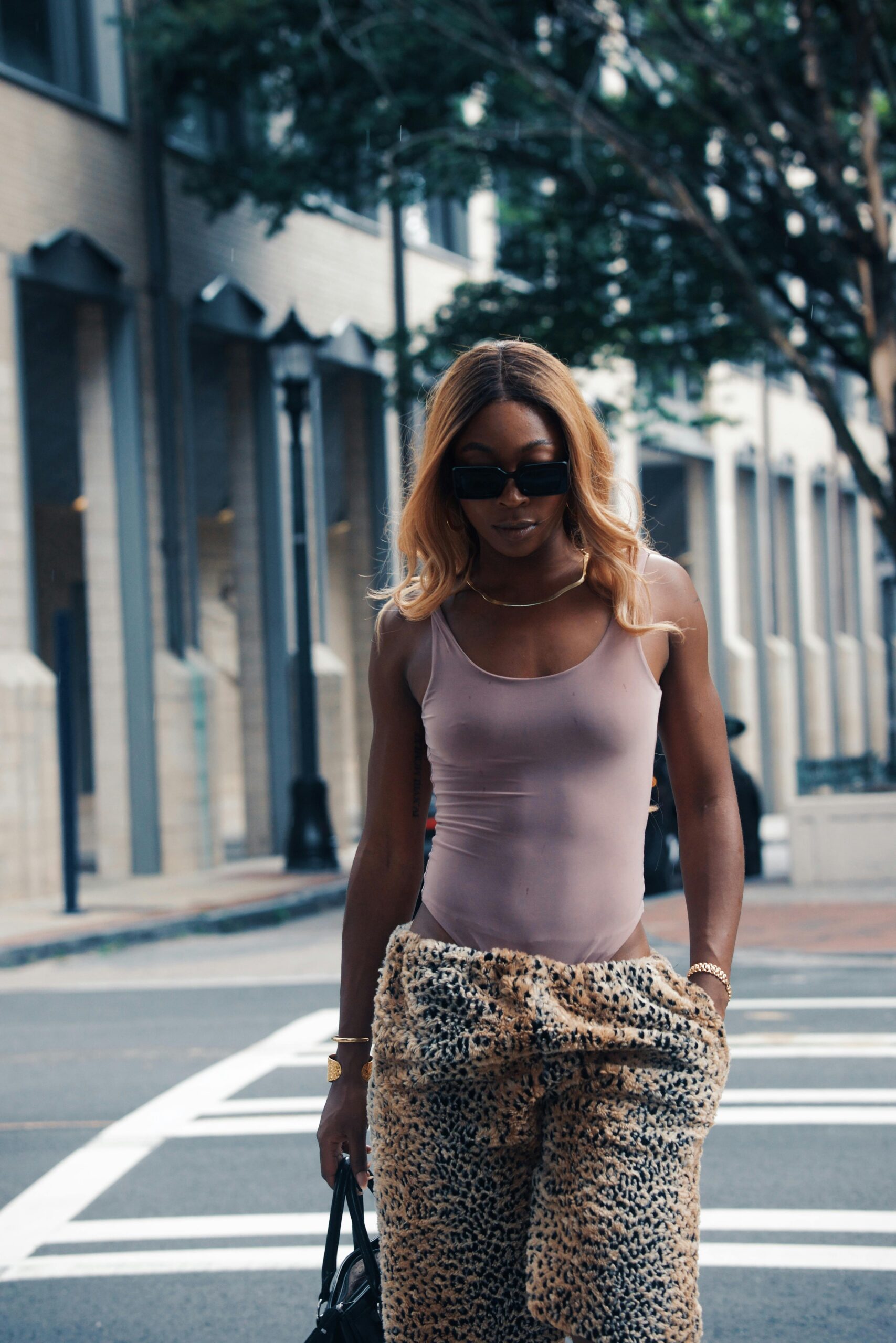 Stylowa kobieta w różowym podkoszulku i spodniach w kształcie geparda spacerująca ulicą Georgetown.