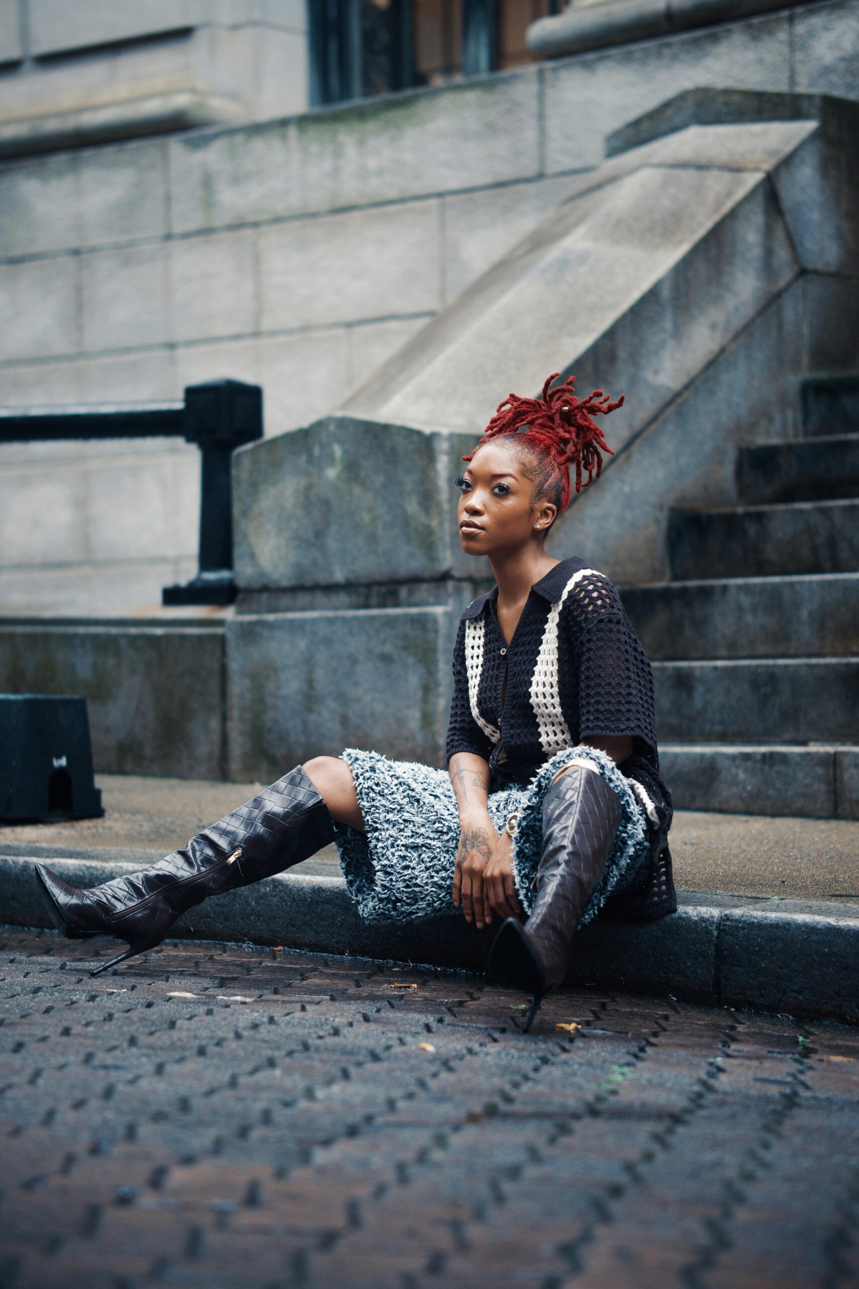 Modna kobieta z rudymi włosami siedząca na schodach miasta w Georgetown w Gujanie.