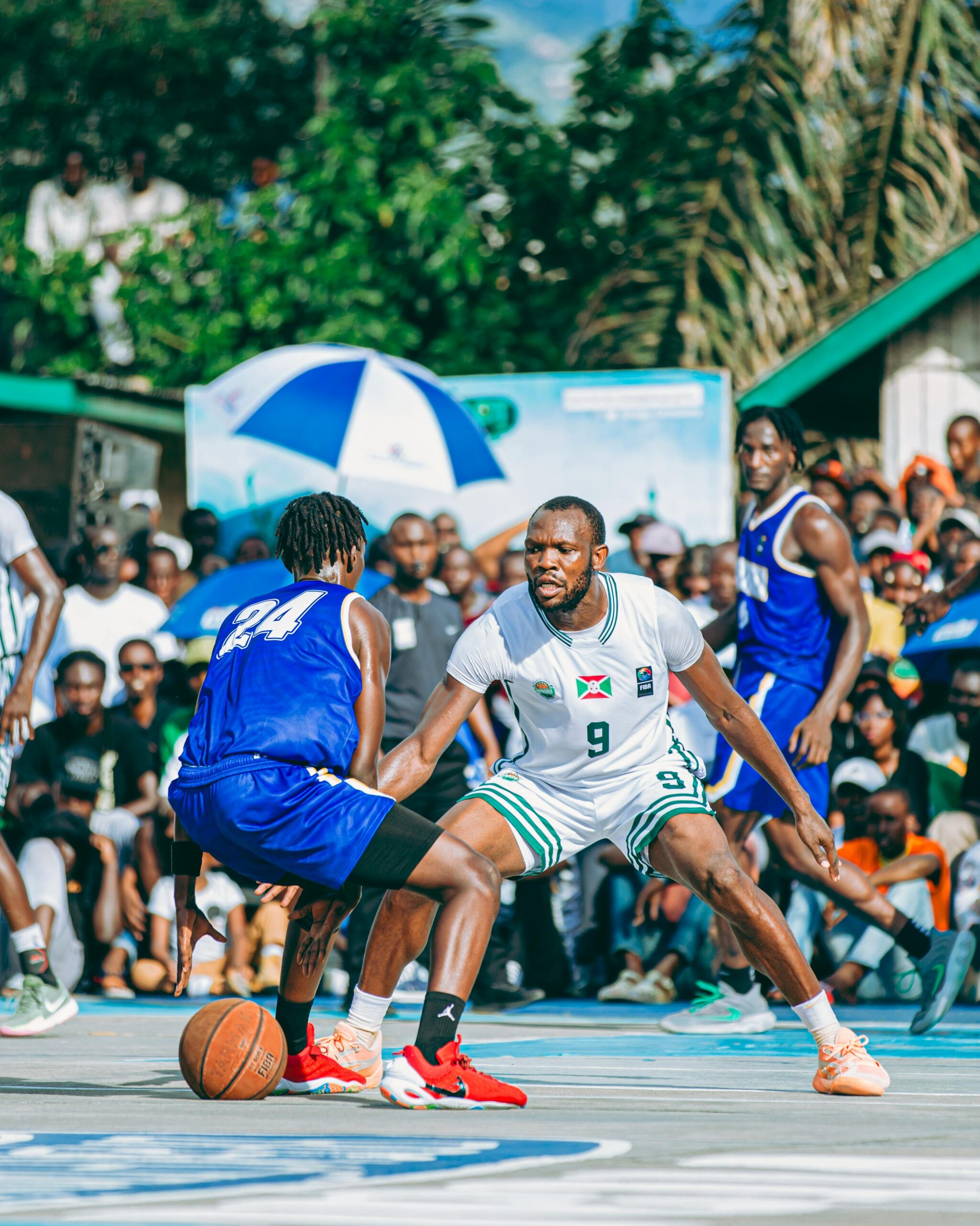 Ekscytujący mecz koszykówki na świeżym powietrzu z tętniącą życiem publicznością w słoneczny dzień.