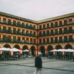 Malowniczy historyczny plac w Hiszpanii z tętniącymi życiem łukami i kawiarniami na świeżym powietrzu, idealny dla miłośników podróży.