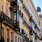 Eleganckie zabytkowe budynki i ozdobne balkony na tętniących życiem ulicach Madrytu.