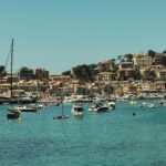 Malowniczy widok na port z żaglówkami i miejskim tłem w słonecznej Hiszpanii.