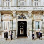 Strażnicy i kawaleria stoją przy wejściu do Pałacu Królewskiego w Madrycie, prezentując hiszpańskie dziedzictwo.