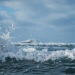 Odkrywanie Parku Güell w Barcelonie. Wibrujące fale oceanu rozbijające się o skały pod zachmurzonym niebem, chwytając moc natury.